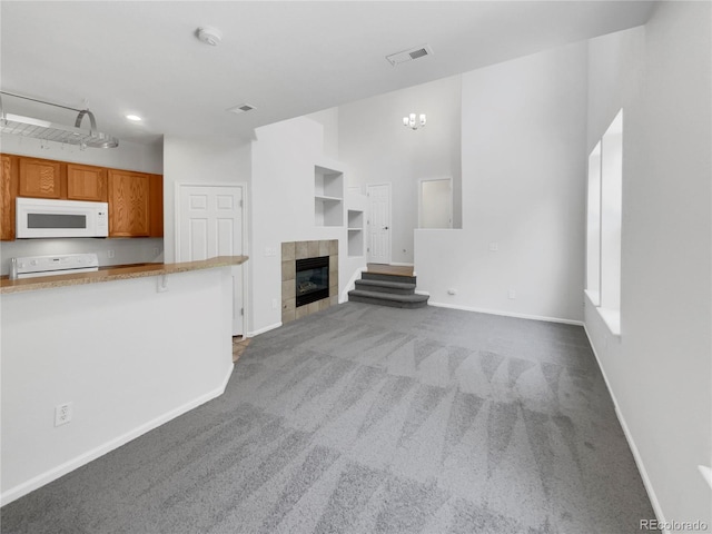 unfurnished living room featuring dark carpet, a tile fireplace, and built in shelves