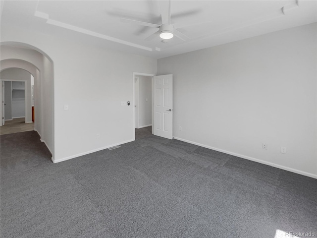 spare room with ceiling fan and dark carpet