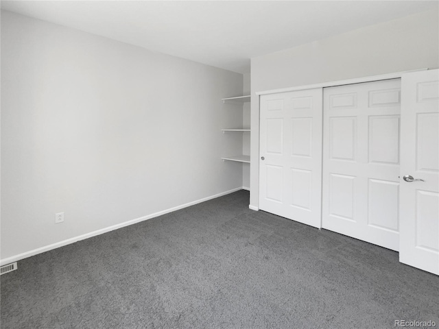 unfurnished bedroom with dark carpet and a closet