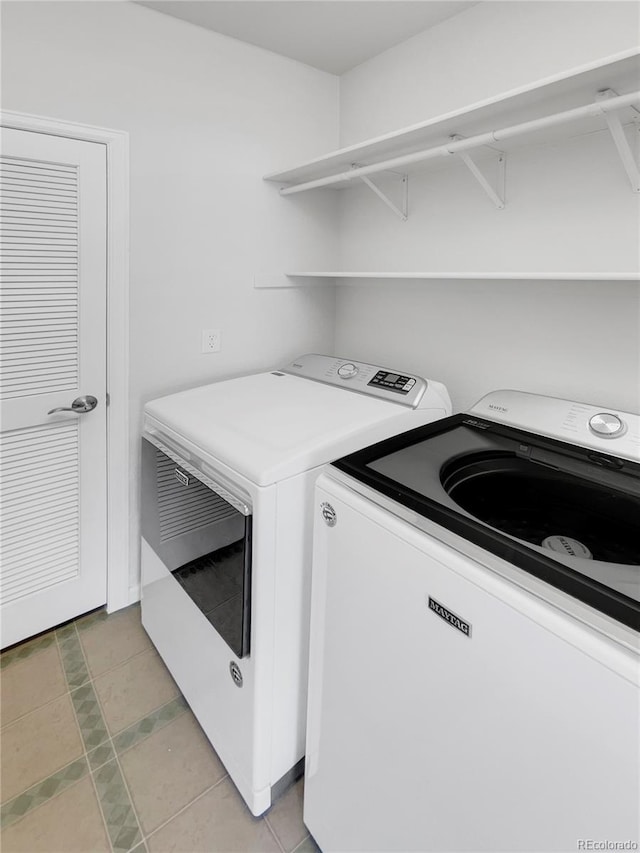 laundry area with independent washer and dryer and light tile patterned floors