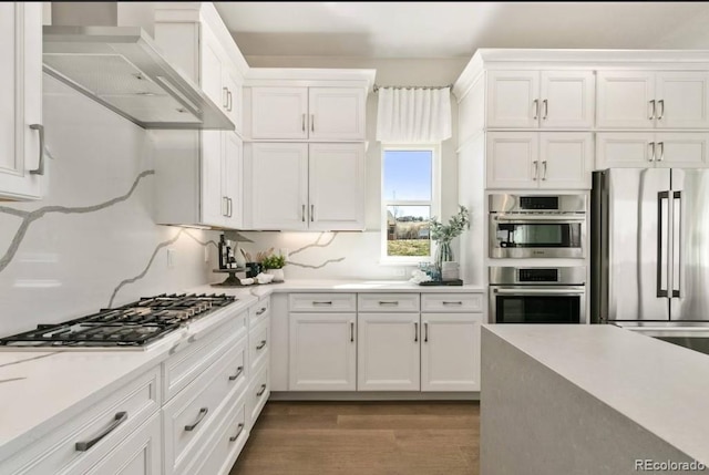 1736 Barefoot Dr, Windsor, CO 80550 - kitchen with appliances with stainless steel finishes, wall chimney exhaust hood, white cabinets, and light countertops