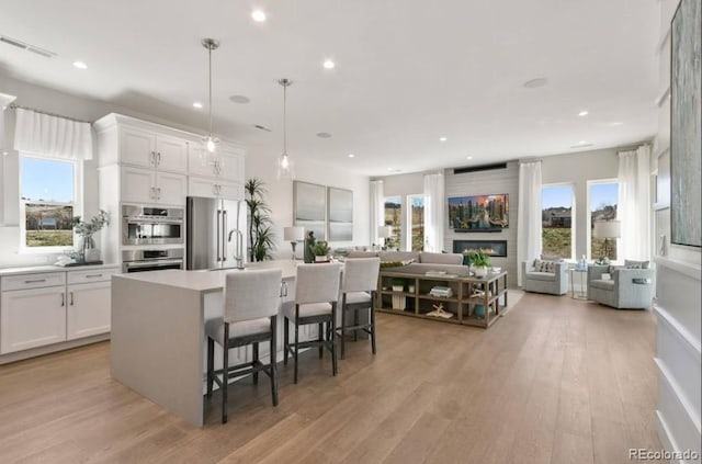 1736 Barefoot Dr, Windsor, CO 80550 - kitchen with appliances with stainless steel finishes, open floor plan, a breakfast bar area, an island with sink, and white cabinetry