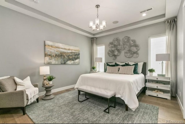 1736 Barefoot Dr, Windsor, CO 80550 - bedroom featuring a raised ceiling, a chandelier, wood finished floors, and multiple windows