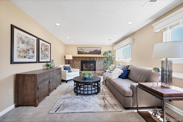 living room featuring a textured ceiling, a brick fireplace, and light colored carpet