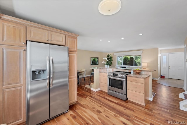 kitchen featuring light hardwood / wood-style floors, stainless steel appliances, light brown cabinetry, and light stone counters