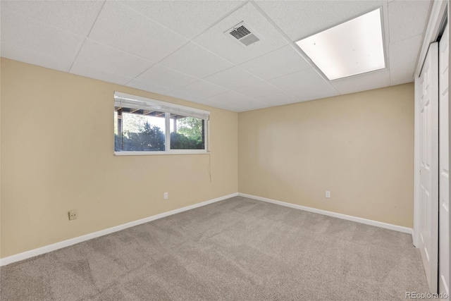 carpeted empty room featuring a paneled ceiling