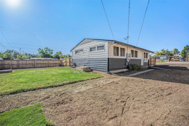 view of side of home featuring fence and a lawn