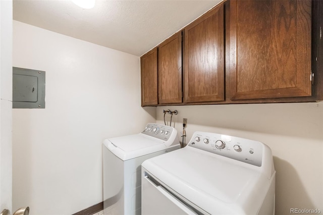 clothes washing area featuring electric panel, washer and clothes dryer, a textured ceiling, and cabinets