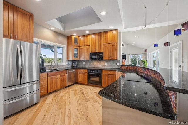 kitchen featuring black appliances, light wood-type flooring, brown cabinetry, tasteful backsplash, and lofted ceiling