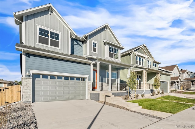 craftsman-style home with a porch, a garage, concrete driveway, stone siding, and board and batten siding