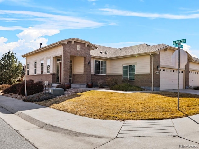 view of front of home featuring a garage, driveway, a front yard, and brick siding