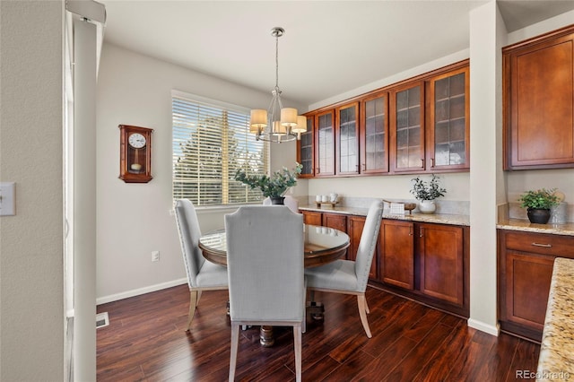 dining area with a chandelier, dark wood-type flooring, and baseboards