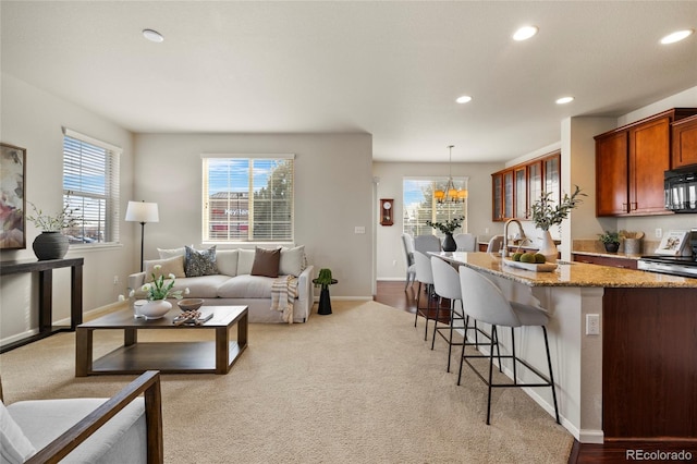 living area with baseboards, light carpet, a chandelier, and recessed lighting