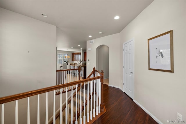 hall with dark wood finished floors, recessed lighting, visible vents, an upstairs landing, and baseboards