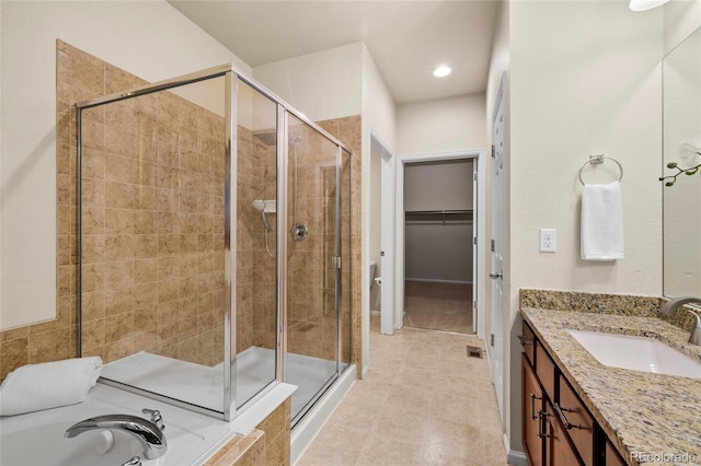 bathroom with a spacious closet, a shower stall, vanity, a tub, and tile patterned flooring