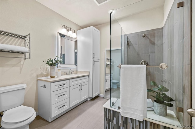 full bath featuring toilet, a shower stall, wood finished floors, and vanity