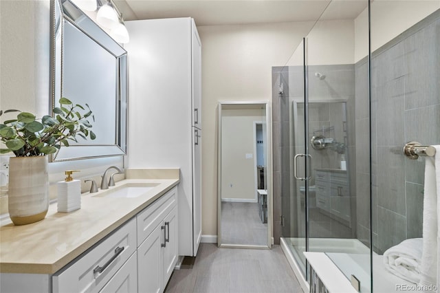 full bath with a stall shower, vanity, and baseboards