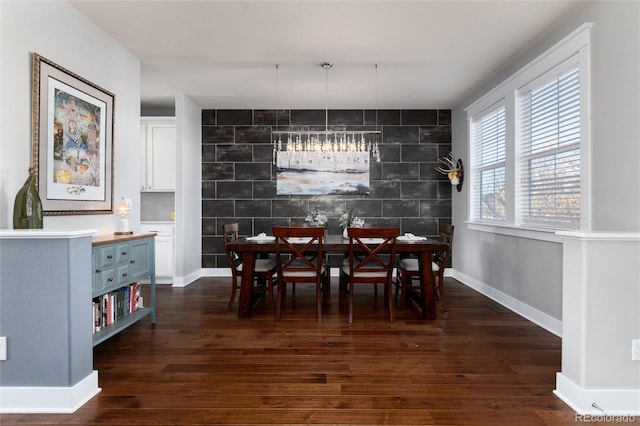 dining room with an accent wall, baseboards, and dark wood-style flooring