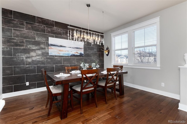 dining room featuring an accent wall, baseboards, and wood finished floors