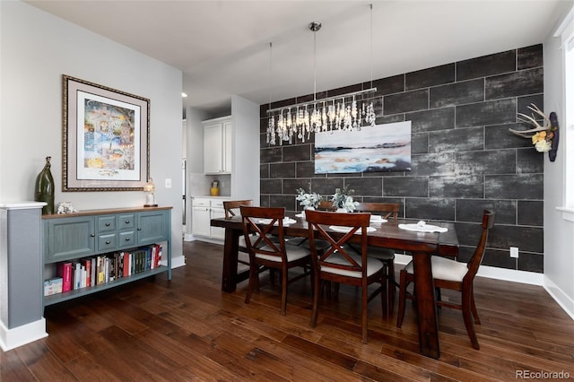 dining area with an accent wall, baseboards, and dark wood finished floors