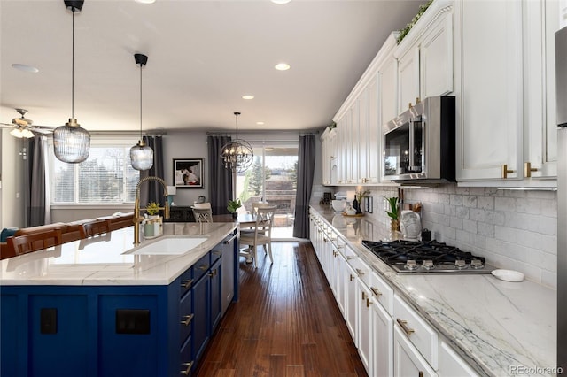 kitchen featuring stainless steel appliances, tasteful backsplash, white cabinetry, a sink, and blue cabinets