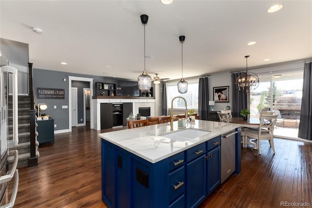 kitchen featuring dark wood-style flooring, a sink, a kitchen island with sink, and blue cabinets