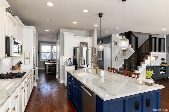 kitchen featuring appliances with stainless steel finishes, a sink, dark wood finished floors, and blue cabinets