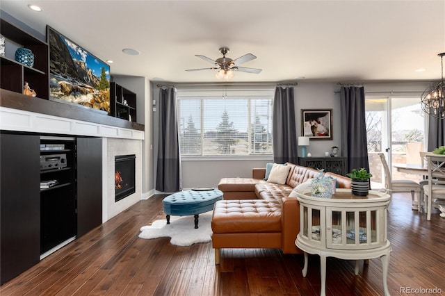 living room featuring dark wood-type flooring, a tiled fireplace, and a wealth of natural light