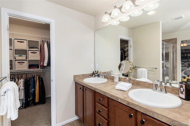 full bath featuring visible vents, a sink, a shower stall, and a spacious closet