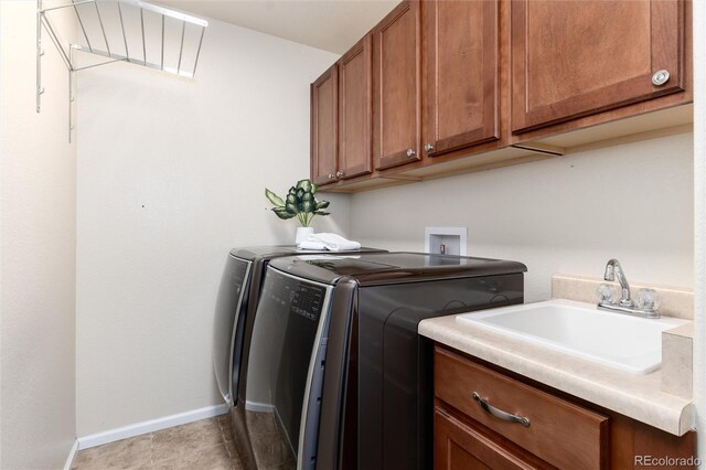 washroom featuring cabinet space, light tile patterned flooring, a sink, independent washer and dryer, and baseboards