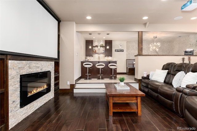 living area featuring recessed lighting, a notable chandelier, a stone fireplace, and wood finished floors