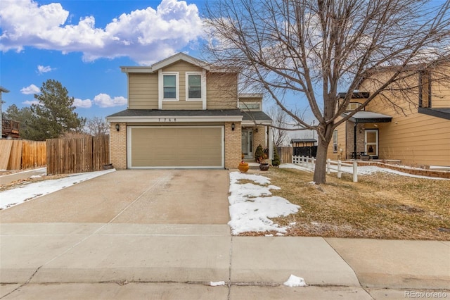 traditional home featuring brick siding, an attached garage, concrete driveway, and fence