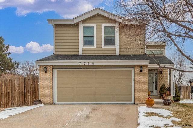 traditional-style home featuring an attached garage, fence, brick siding, and driveway