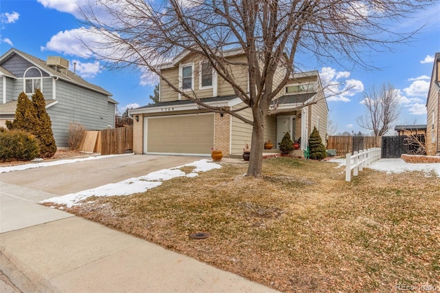 traditional home with brick siding, driveway, an attached garage, and fence