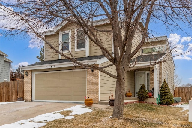 traditional home with a garage, brick siding, concrete driveway, and fence