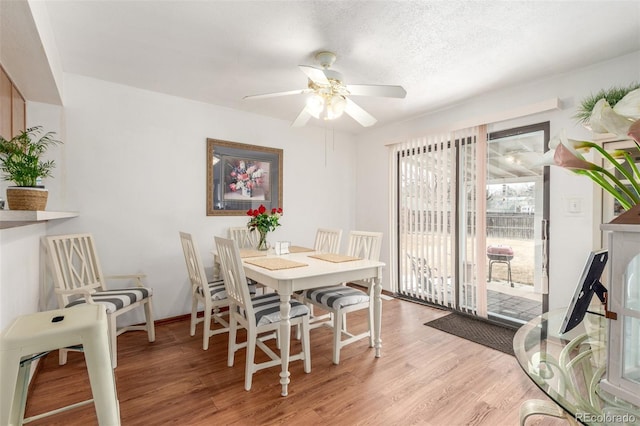 dining room with light wood-style flooring, a textured ceiling, and ceiling fan