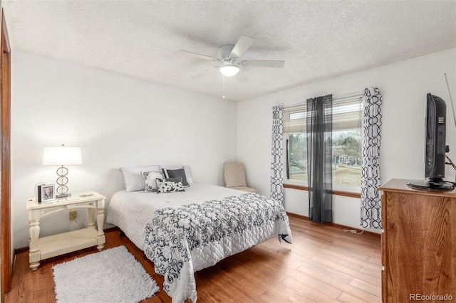 bedroom with a ceiling fan, wood finished floors, and a textured ceiling