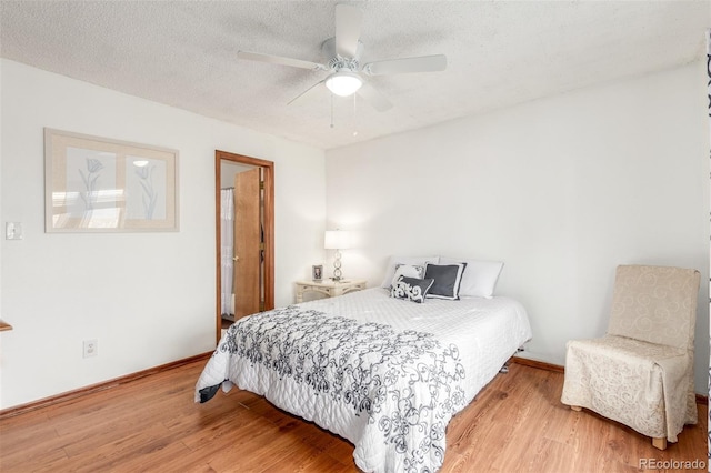 bedroom featuring ceiling fan, light wood-style flooring, baseboards, and a textured ceiling