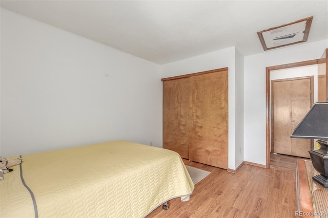 bedroom featuring light wood-type flooring, baseboards, and a closet