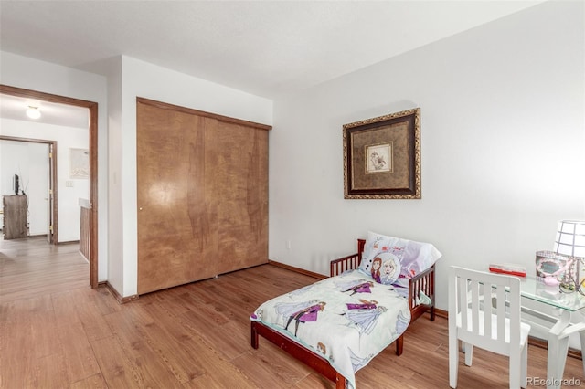 bedroom with a closet, baseboards, and wood finished floors