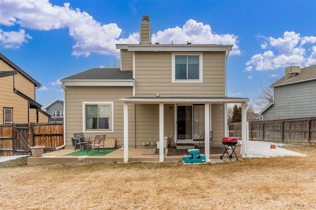 rear view of house with a patio area, a chimney, and a fenced backyard