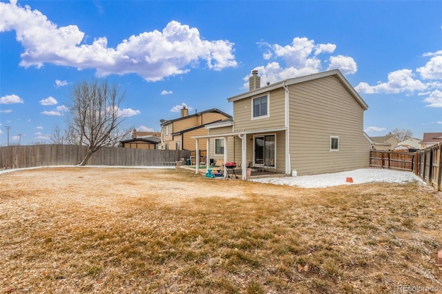 back of property featuring a patio, a lawn, a fenced backyard, and a chimney