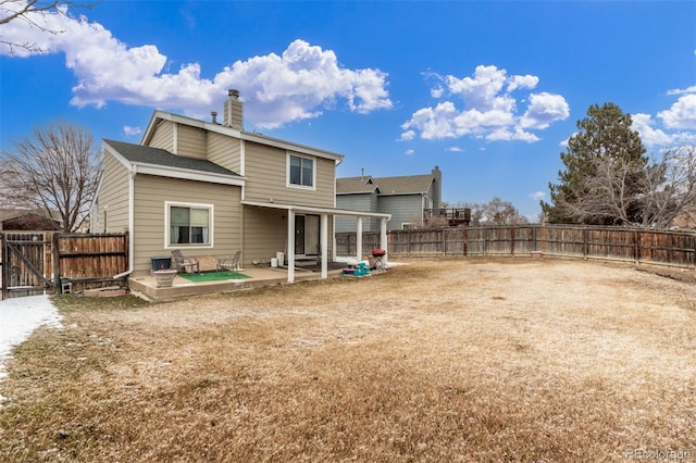 rear view of property with a patio area, a gate, a fenced backyard, and a chimney