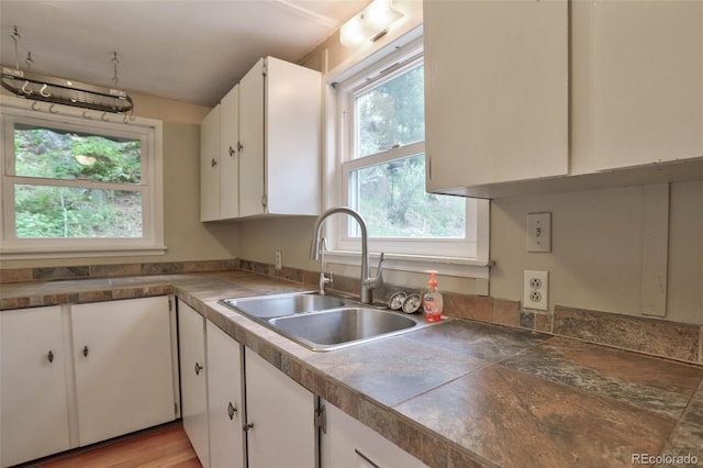 kitchen featuring light wood-type flooring, white cabinetry, and sink