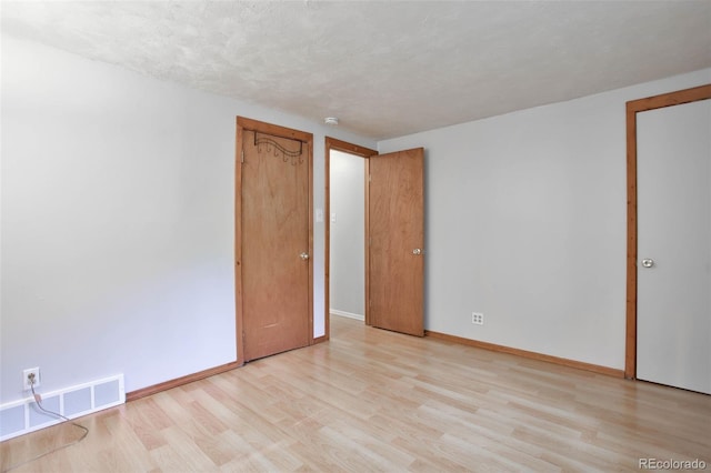 spare room featuring light wood-type flooring and a textured ceiling