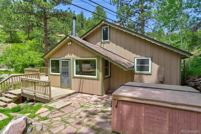 back of property with a wooden deck and a hot tub