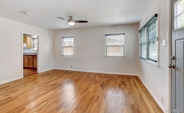 spare room with ceiling fan, plenty of natural light, sink, and light wood-type flooring