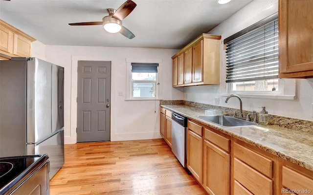 kitchen featuring sink, light hardwood / wood-style flooring, ceiling fan, appliances with stainless steel finishes, and light stone counters