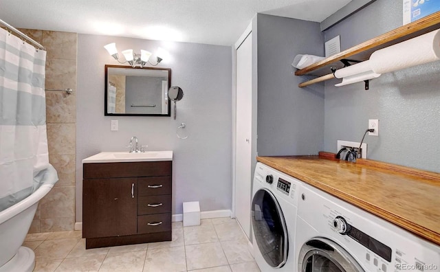 clothes washing area with sink, light tile patterned floors, a textured ceiling, and independent washer and dryer