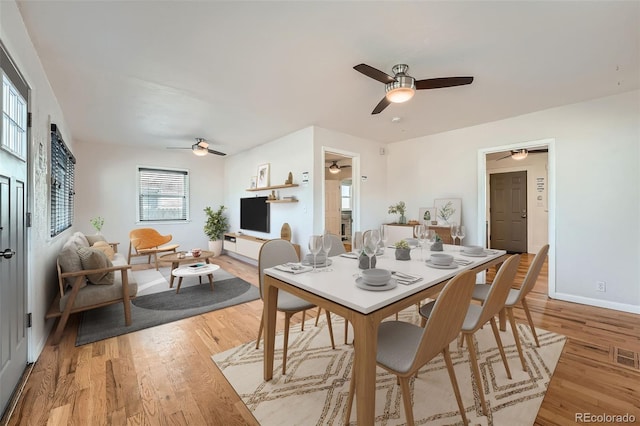 dining area with light wood-style flooring, baseboards, and ceiling fan